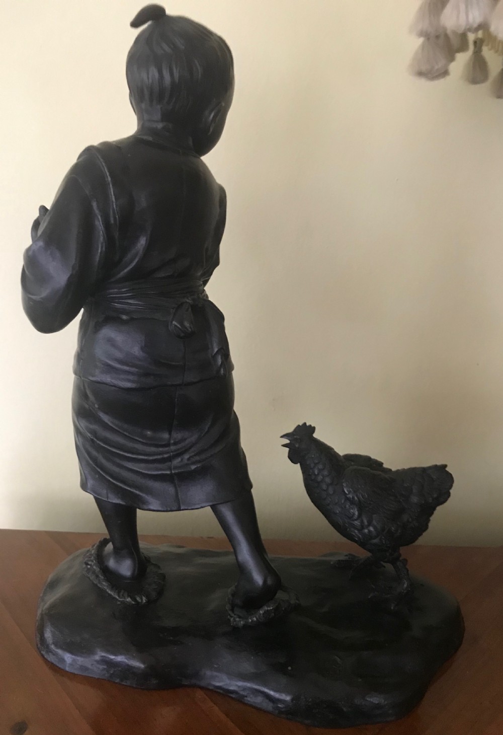 A dark bronze Japanese okimono sculpture depicting a boy in traditional kimono and geta sandals walking beside a chicken on a cast naturalistic base. View III