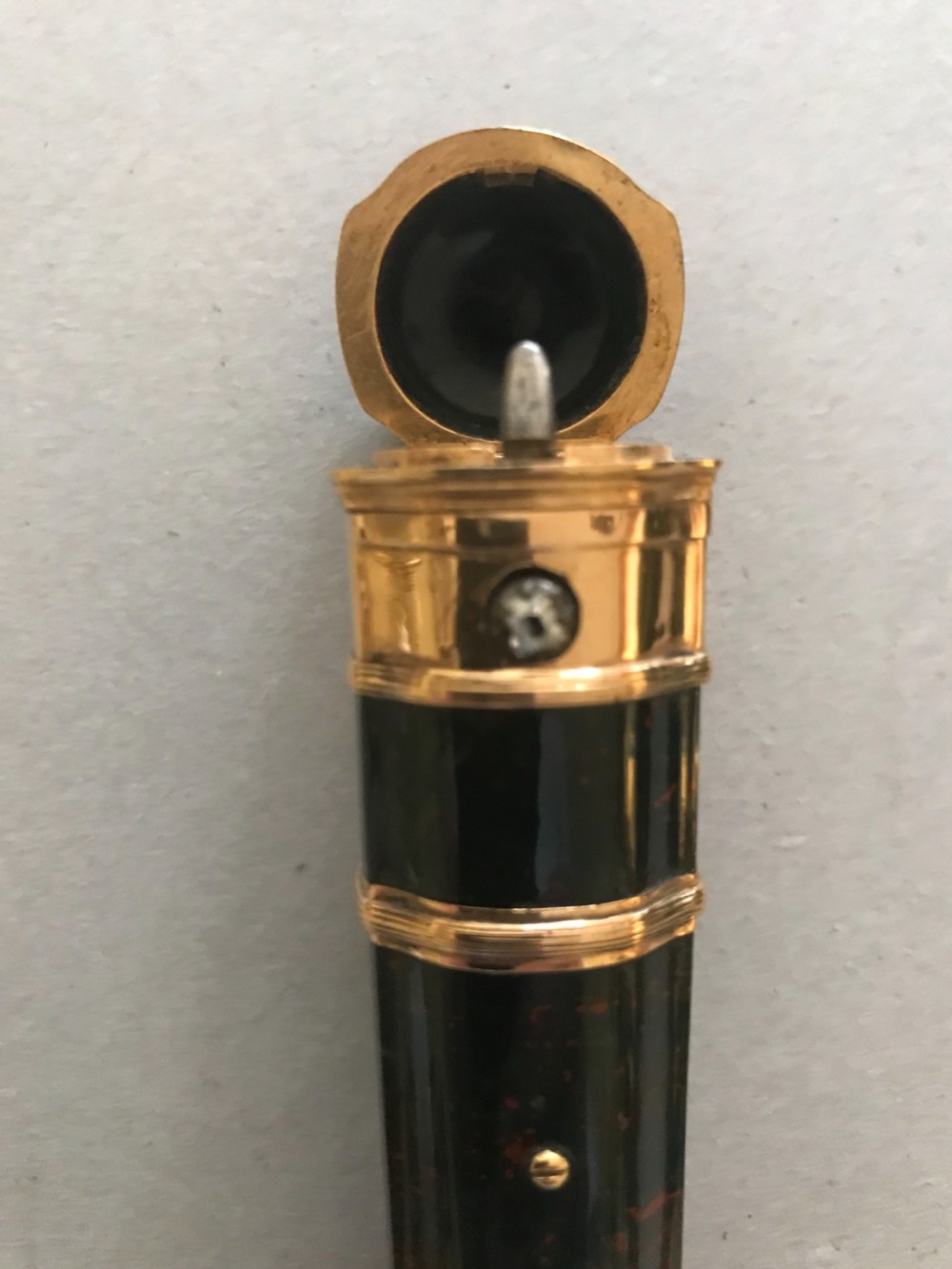 A cylindrical dark green bloodstone etui featuring reeded gold mounts, subtle red mineral inclusions, and a stone-set push-button catch. View III