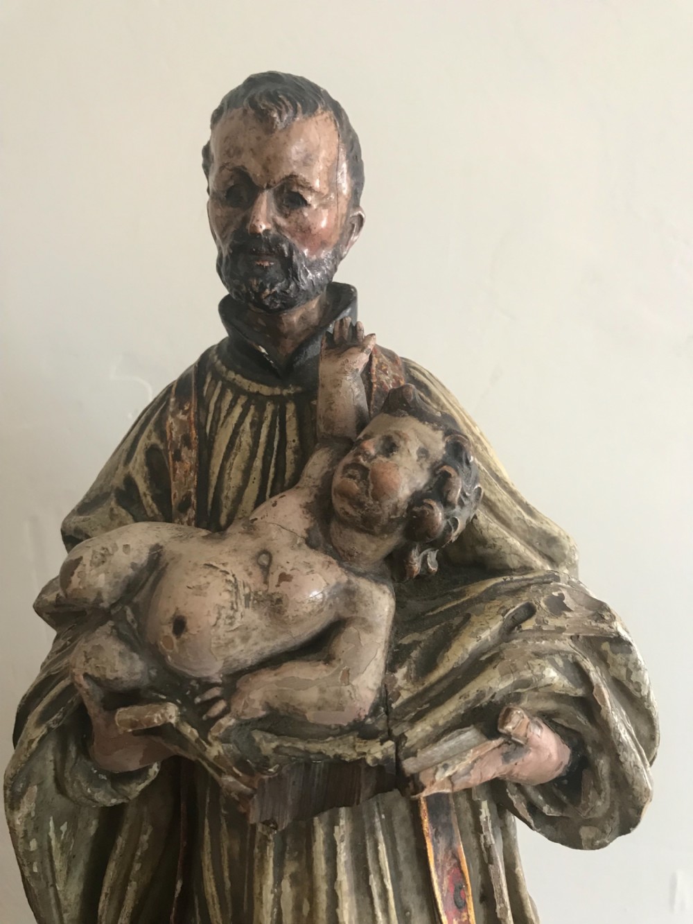 A late 18th-century polychromed wood carving depicting a standing bearded saint holding an infant, set upon a carved pedestal base. View II
