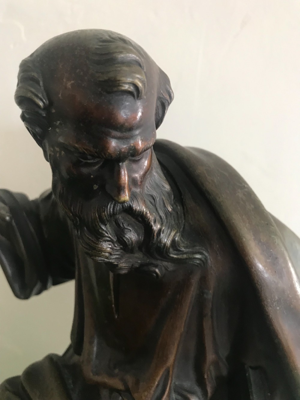 A patinated dark bronze sculpture depicting a draped, bearded ancient scholar seated on a green veined marble base. View II