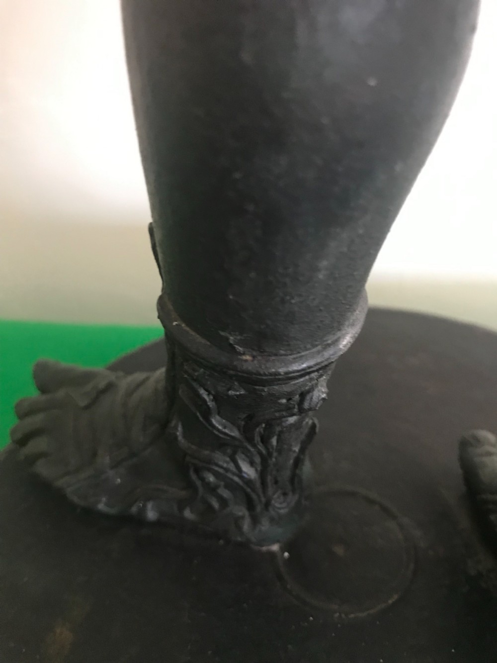 A dark patinated bronze sculpture depicting a standing nude male figure on a round stepped base. View V