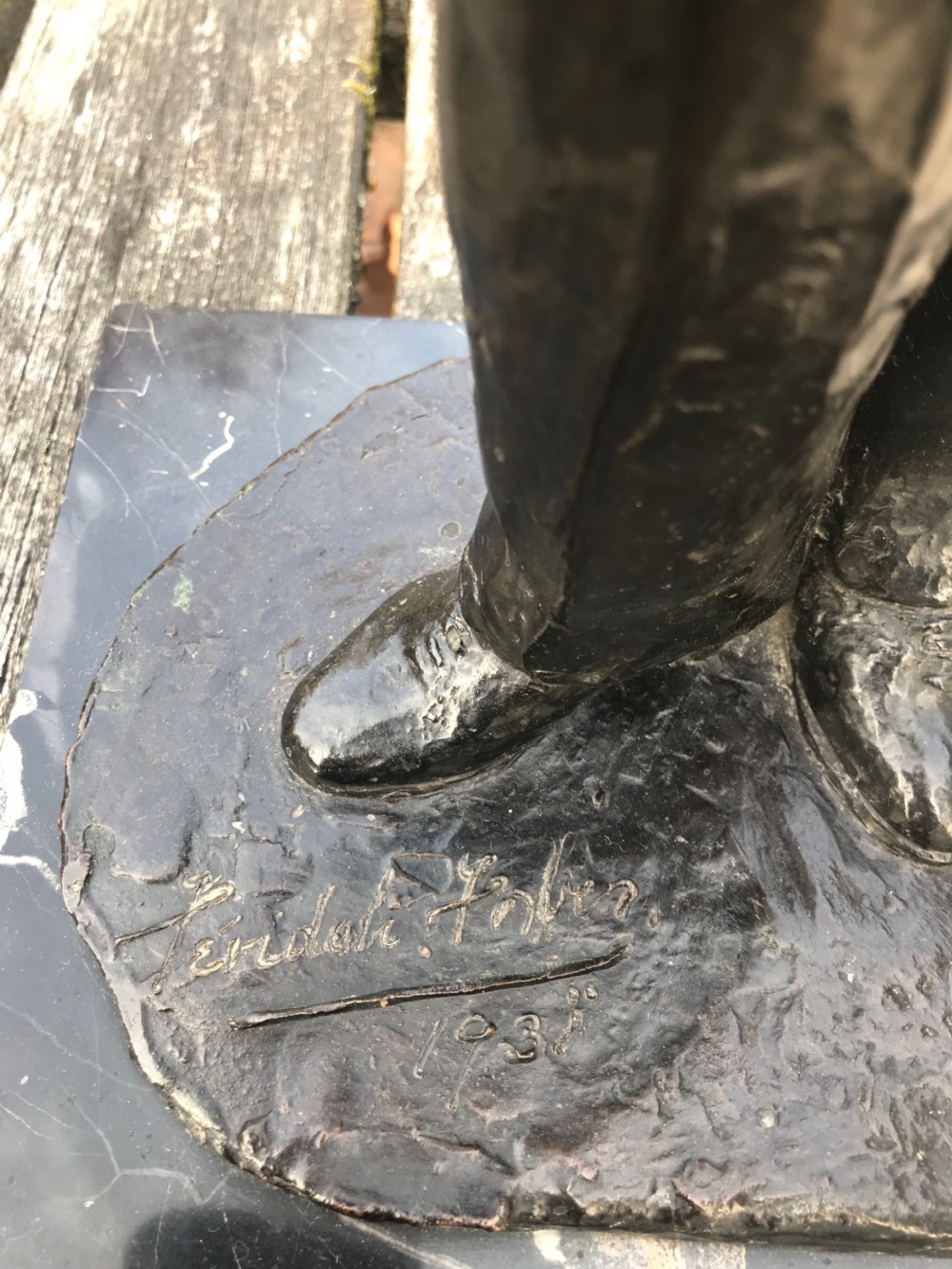A dark patinated bronze statue depicting a standing man in a suit, mounted on a black marble base. View II