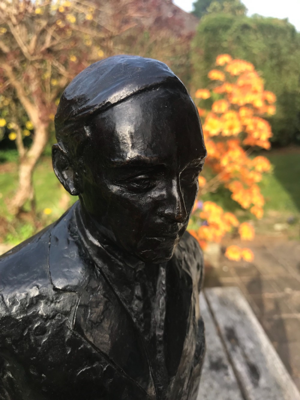 A dark patinated bronze statue depicting a standing man in a suit, mounted on a black marble base. View III