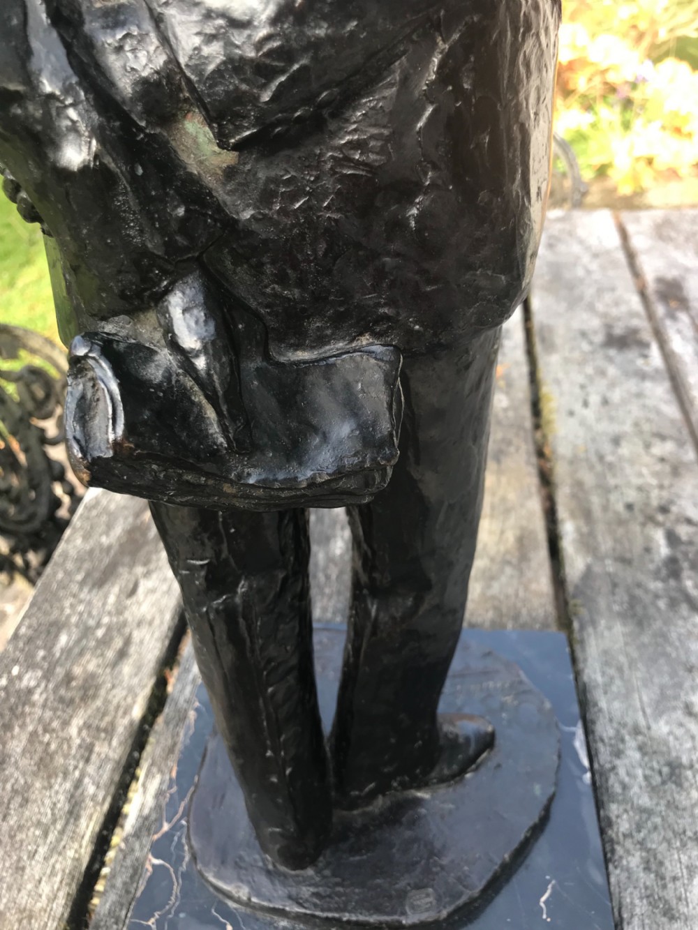 A dark patinated bronze statue depicting a standing man in a suit, mounted on a black marble base. View VII
