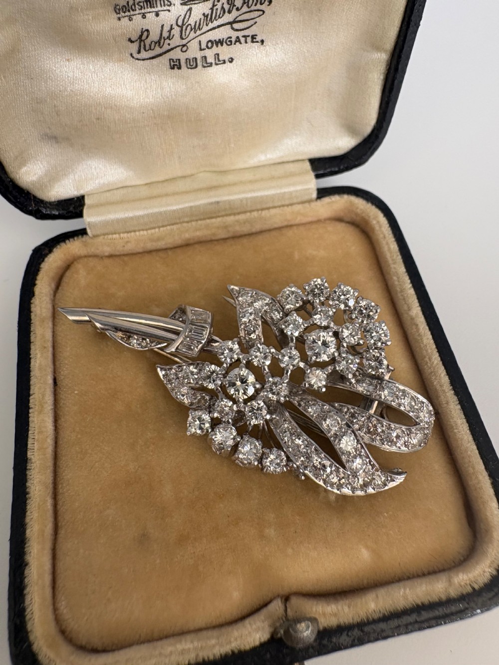 A 1930s platinum spray brooch densely set with round brilliant and baguette-cut diamonds arranged in stylized ribbon loops. View II