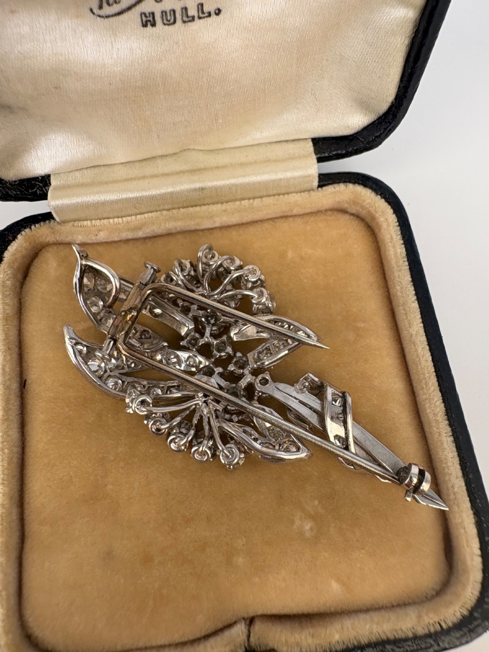 A 1930s platinum spray brooch densely set with round brilliant and baguette-cut diamonds arranged in stylized ribbon loops. View IV