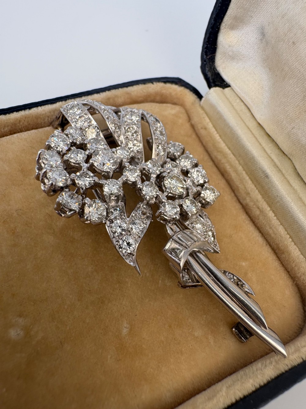 A 1930s platinum spray brooch densely set with round brilliant and baguette-cut diamonds arranged in stylized ribbon loops. View V