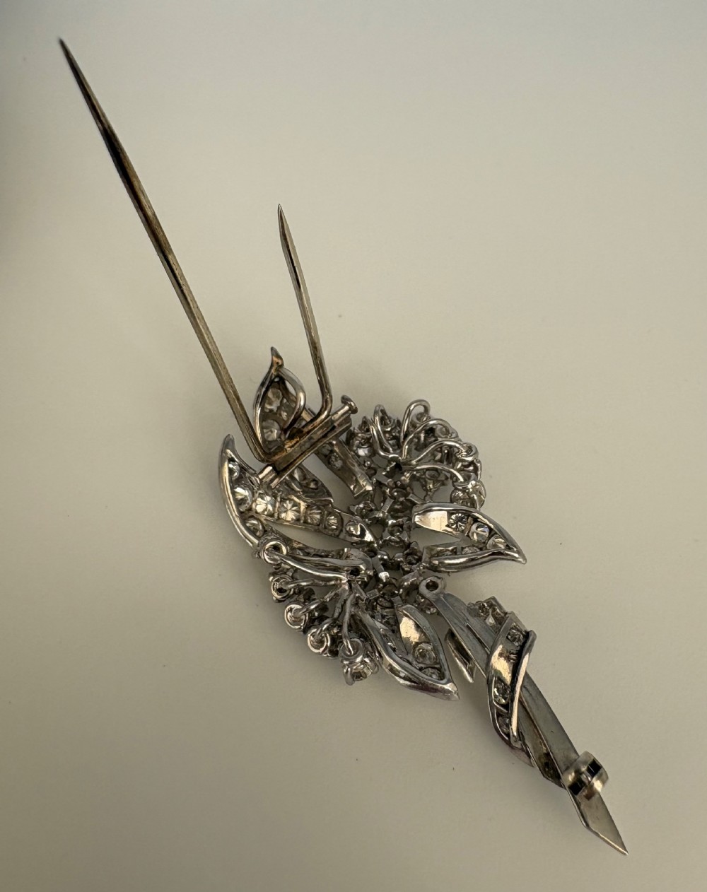A 1930s platinum spray brooch densely set with round brilliant and baguette-cut diamonds arranged in stylized ribbon loops. View VI