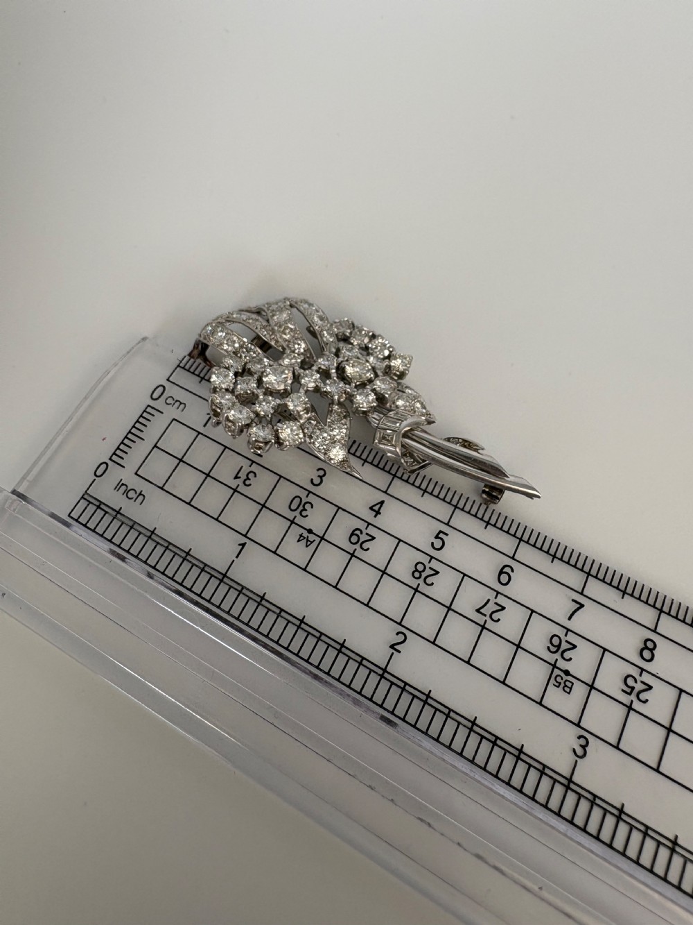 A 1930s platinum spray brooch densely set with round brilliant and baguette-cut diamonds arranged in stylized ribbon loops. View VII