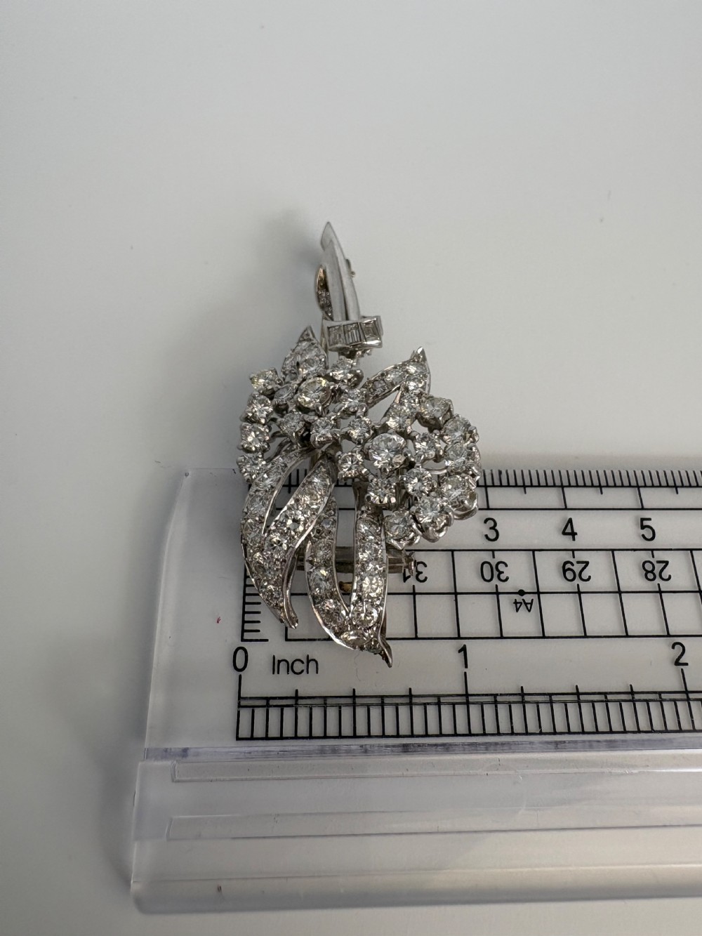 A 1930s platinum spray brooch densely set with round brilliant and baguette-cut diamonds arranged in stylized ribbon loops. View VIII