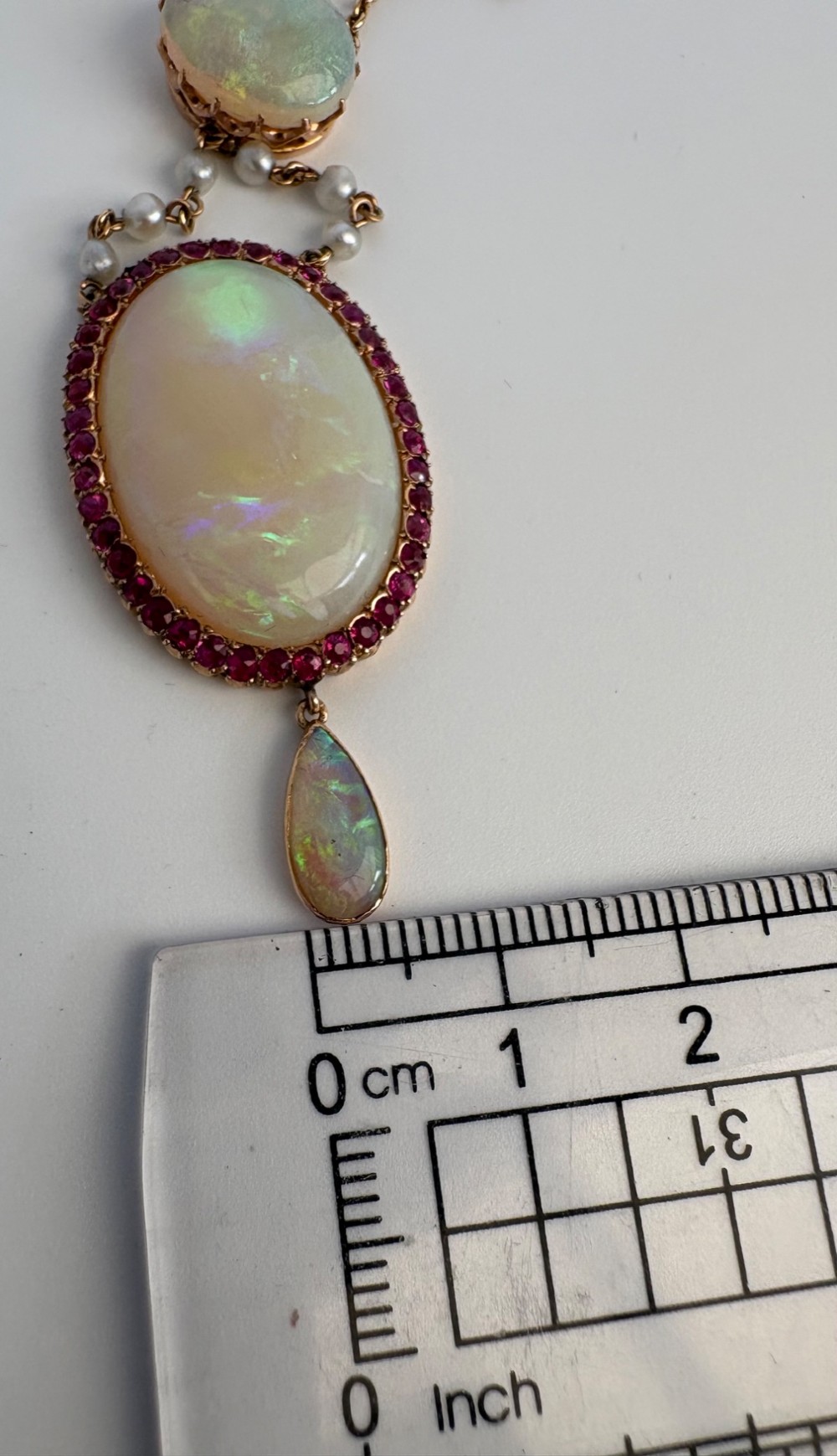 An antique Victorian 15ct yellow gold lavalier pendant set with two oval cabochon opals, a halo of rubies, and seed pearl connectors. View XII