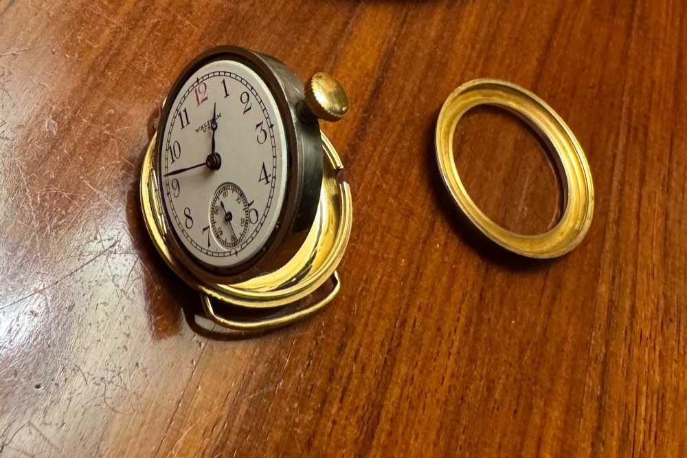 A 1920s 18ct gold Waltham wristwatch with a white enamel dial, black Arabic numerals, a red 12 marker, and a black woven strap. View XIII