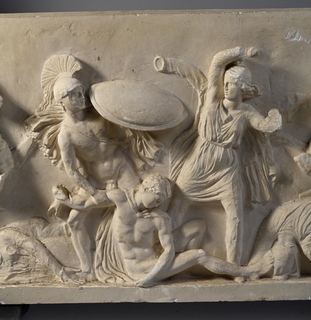 A horizontal cream plaster bas-relief panel depicting a classical battle scene between cavalry warriors and shield-bearing soldiers. View III