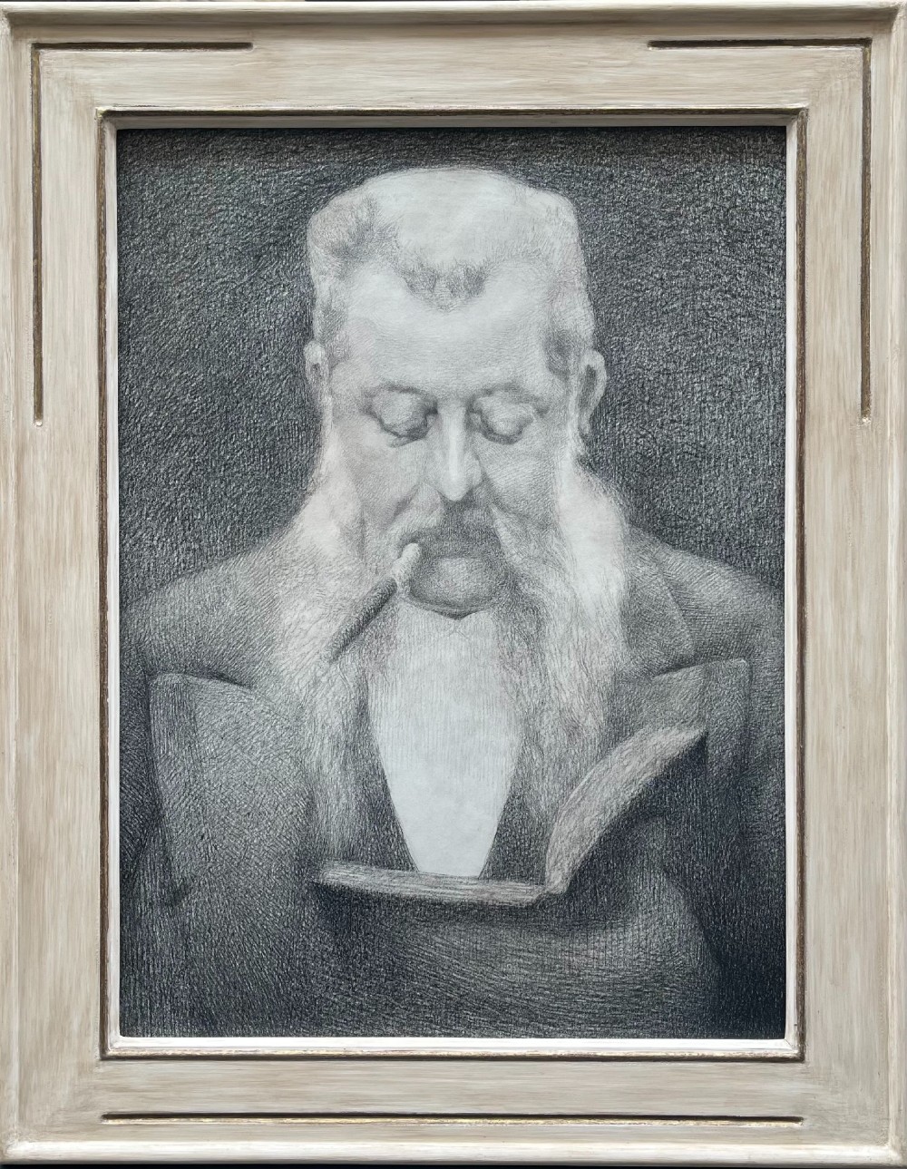 A framed monochrome pencil drawing depicting a bearded gentleman holding a cigar and an open book, enclosed in a light-coloured wooden frame.