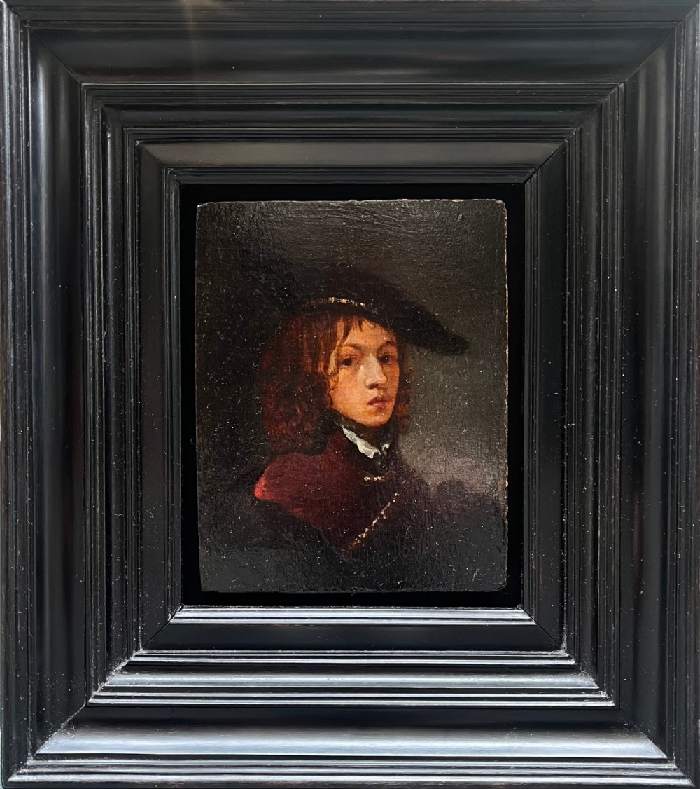 An antique oil portrait depicting a young man wearing a wide-brimmed cap, presented within a multi-moulded black ebonised frame.