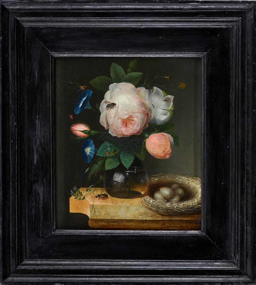 A Flemish Baroque oil painting depicting pink roses and morning glories in a clear glass vase beside a bird nest containing eggs, set within an ebonised wooden frame.