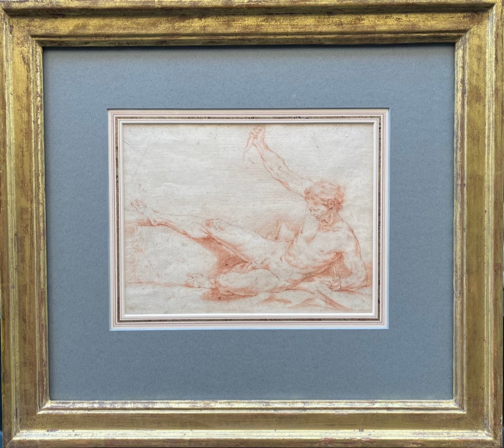 An eighteenth-century red chalk drawing of a reclining male figure mounted on a grey mat and housed in a gilded frame.