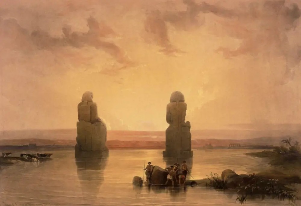 A 19th-century Orientalist landscape artwork depicting two colossal stone statues standing in calm waters under a glowing warm ochre sky.