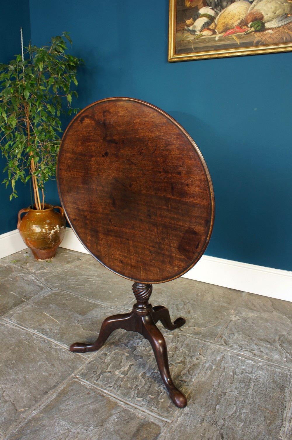 An 18th century dark mahogany tripod table with a circular dished top set on a turned column with cabriole legs and pad feet. View VII