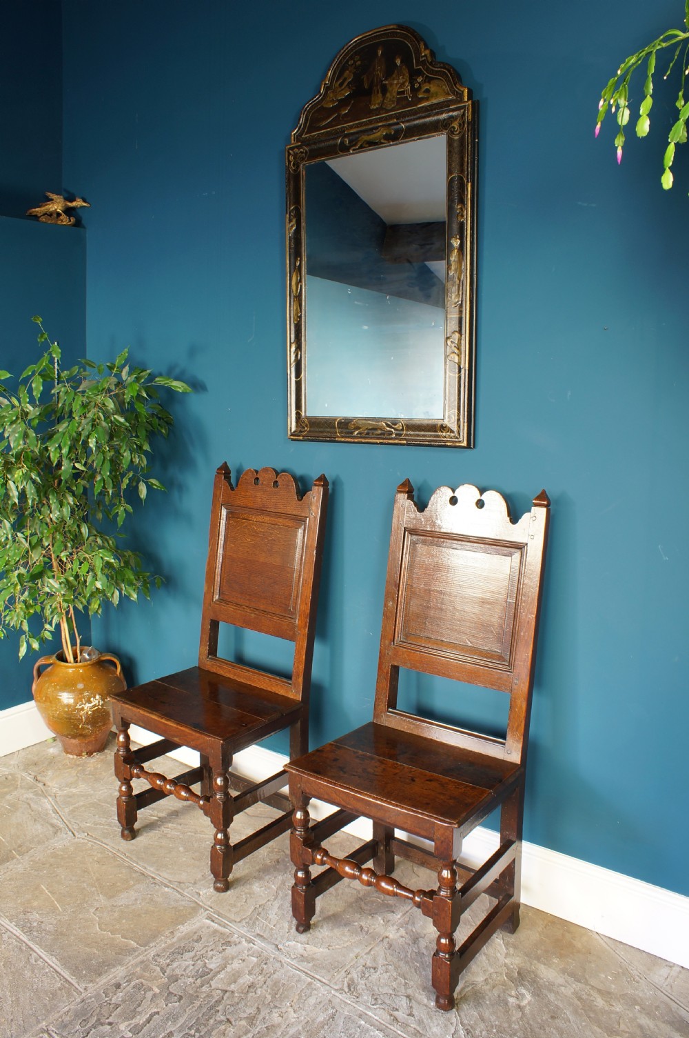 A pair of 17th-century dark oak Lancashire backstool chairs with panelled backs, shaped cresting rails, and turned front legs. View II