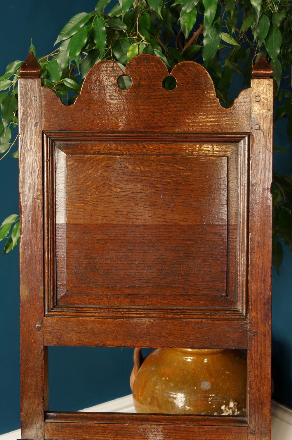 A pair of 17th-century dark oak Lancashire backstool chairs with panelled backs, shaped cresting rails, and turned front legs. View VI