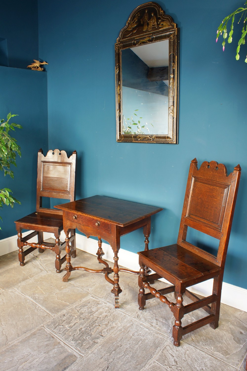 A pair of 17th-century dark oak Lancashire backstool chairs with panelled backs, shaped cresting rails, and turned front legs. View IX