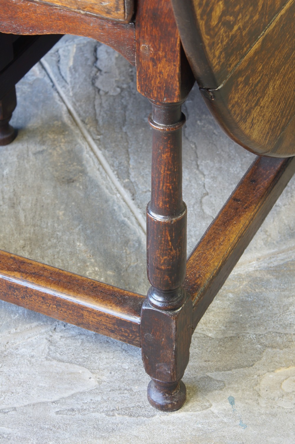A large 18th-century dark oak gateleg dining table with a circular drop-leaf top supported by turned legs and stretchers. View III
