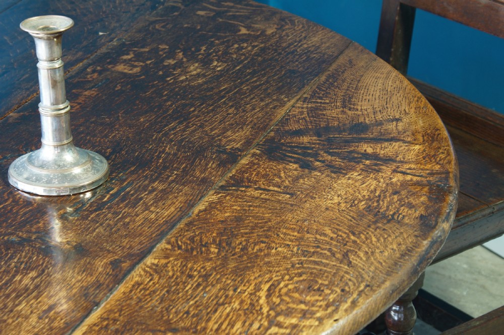 A large 18th-century dark oak gateleg dining table with a circular drop-leaf top supported by turned legs and stretchers. View XIII