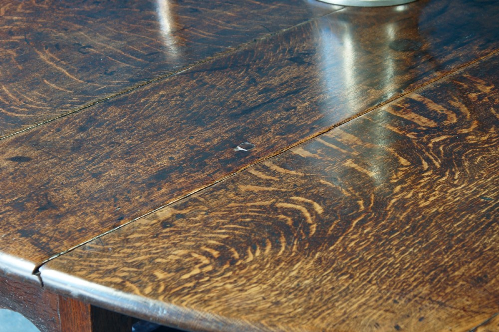A large 18th-century dark oak gateleg dining table with a circular drop-leaf top supported by turned legs and stretchers. View XIV
