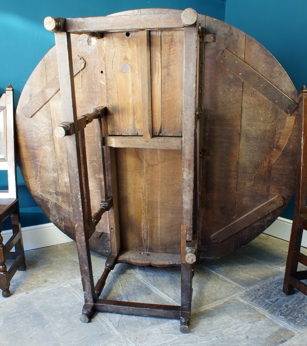 A large 18th-century dark oak gateleg dining table with a circular drop-leaf top supported by turned legs and stretchers. View XVI