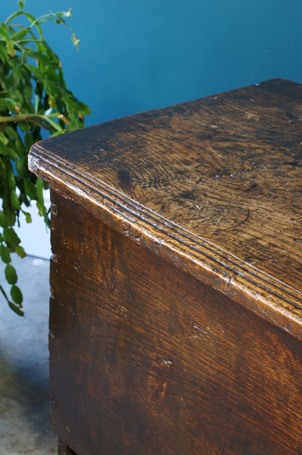 A dark brown 17th-century six-plank oak coffer featuring a flat top lid, iron lockplate, and bootjack side ends. View III