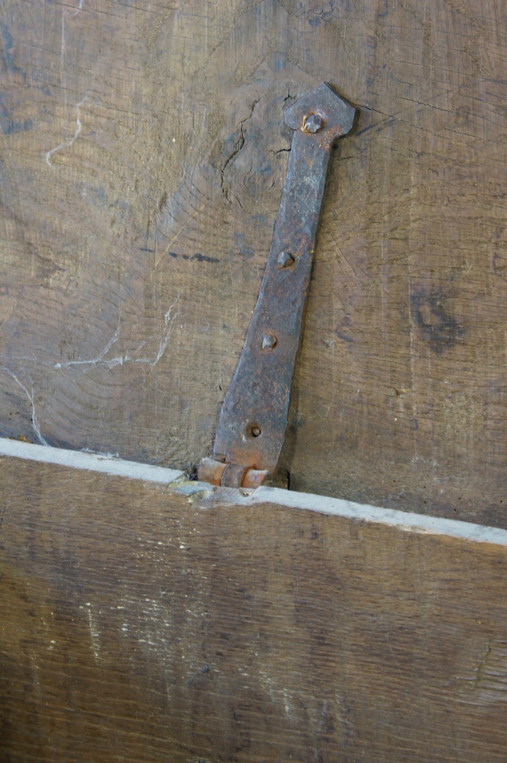 A dark brown 17th-century six-plank oak coffer featuring a flat top lid, iron lockplate, and bootjack side ends. View VI