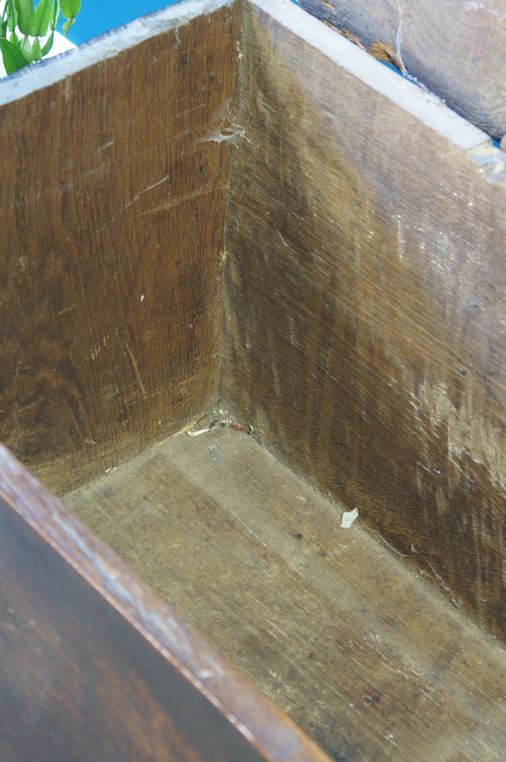 A dark brown 17th-century six-plank oak coffer featuring a flat top lid, iron lockplate, and bootjack side ends. View VII