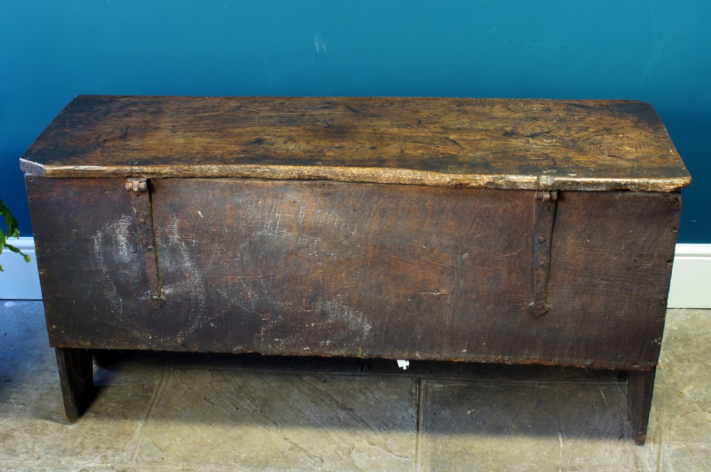 A dark brown 17th-century six-plank oak coffer featuring a flat top lid, iron lockplate, and bootjack side ends. View VIII