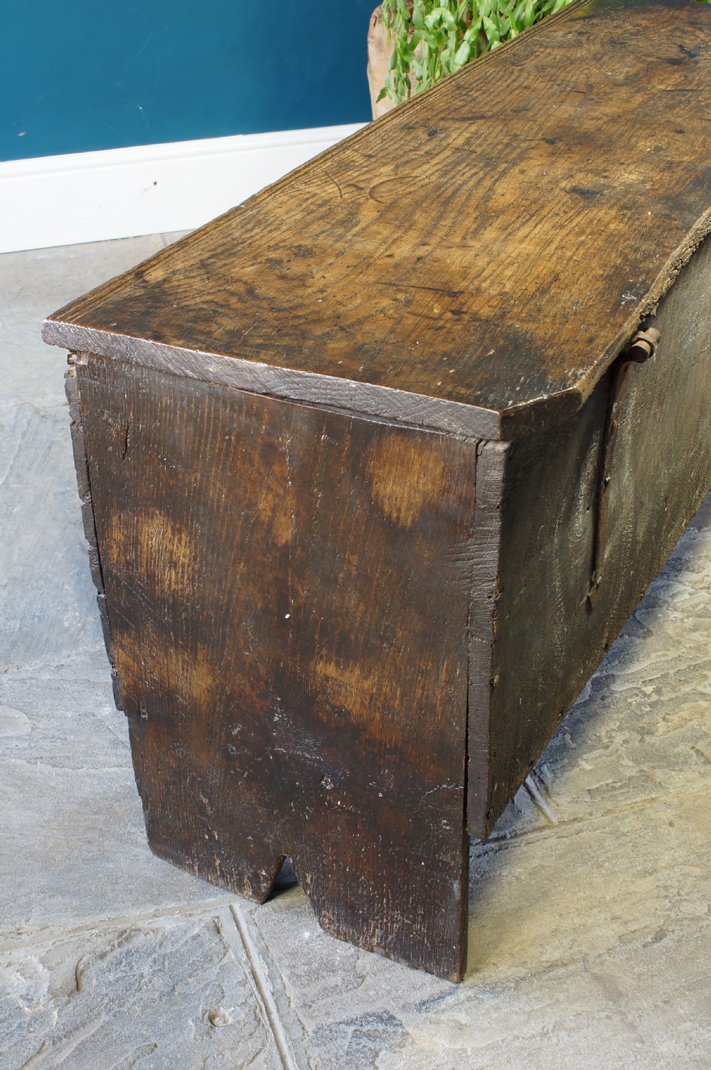 A dark brown 17th-century six-plank oak coffer featuring a flat top lid, iron lockplate, and bootjack side ends. View XI