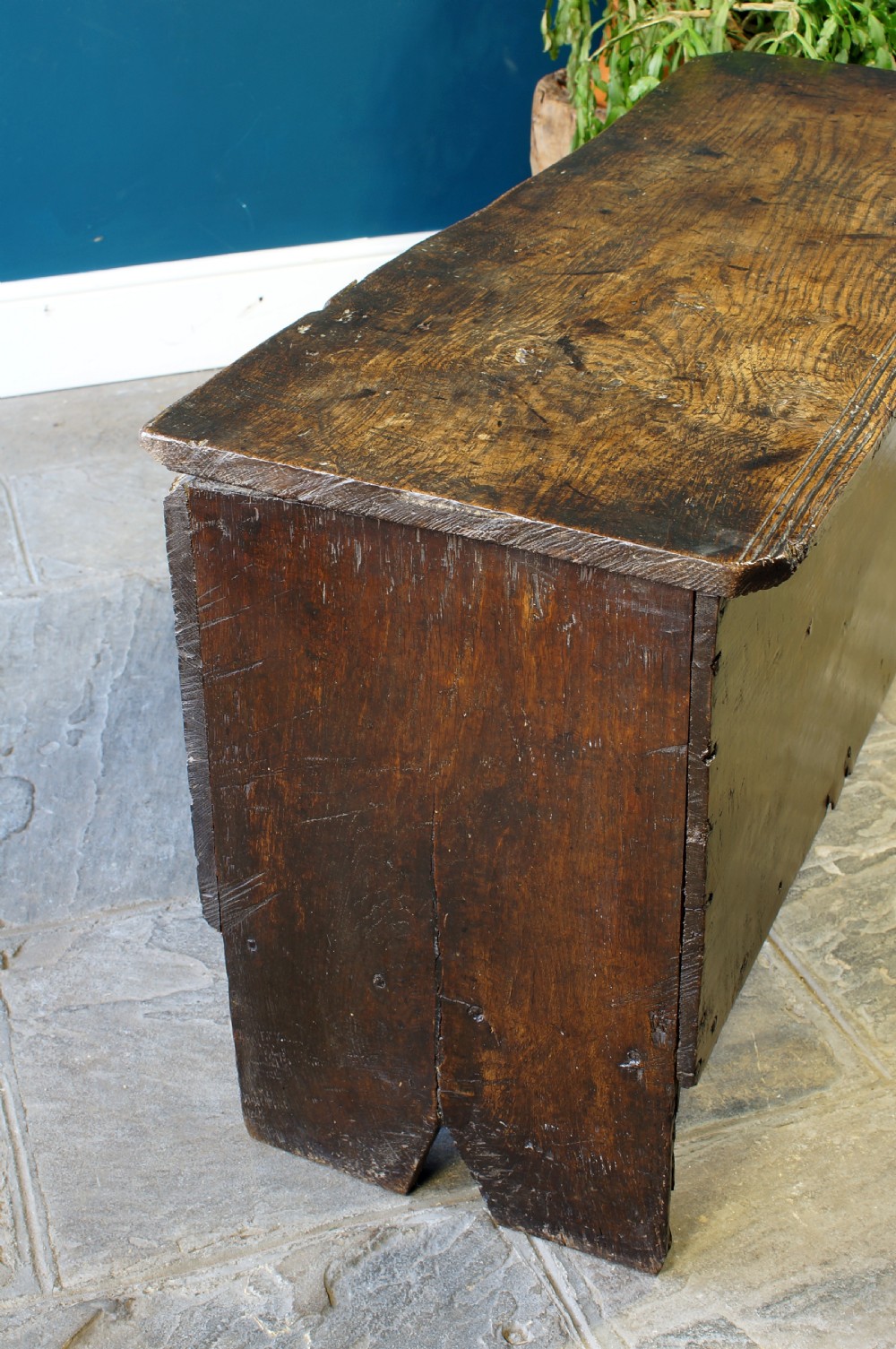 A dark brown 17th-century six-plank oak coffer featuring a flat top lid, iron lockplate, and bootjack side ends. View XII