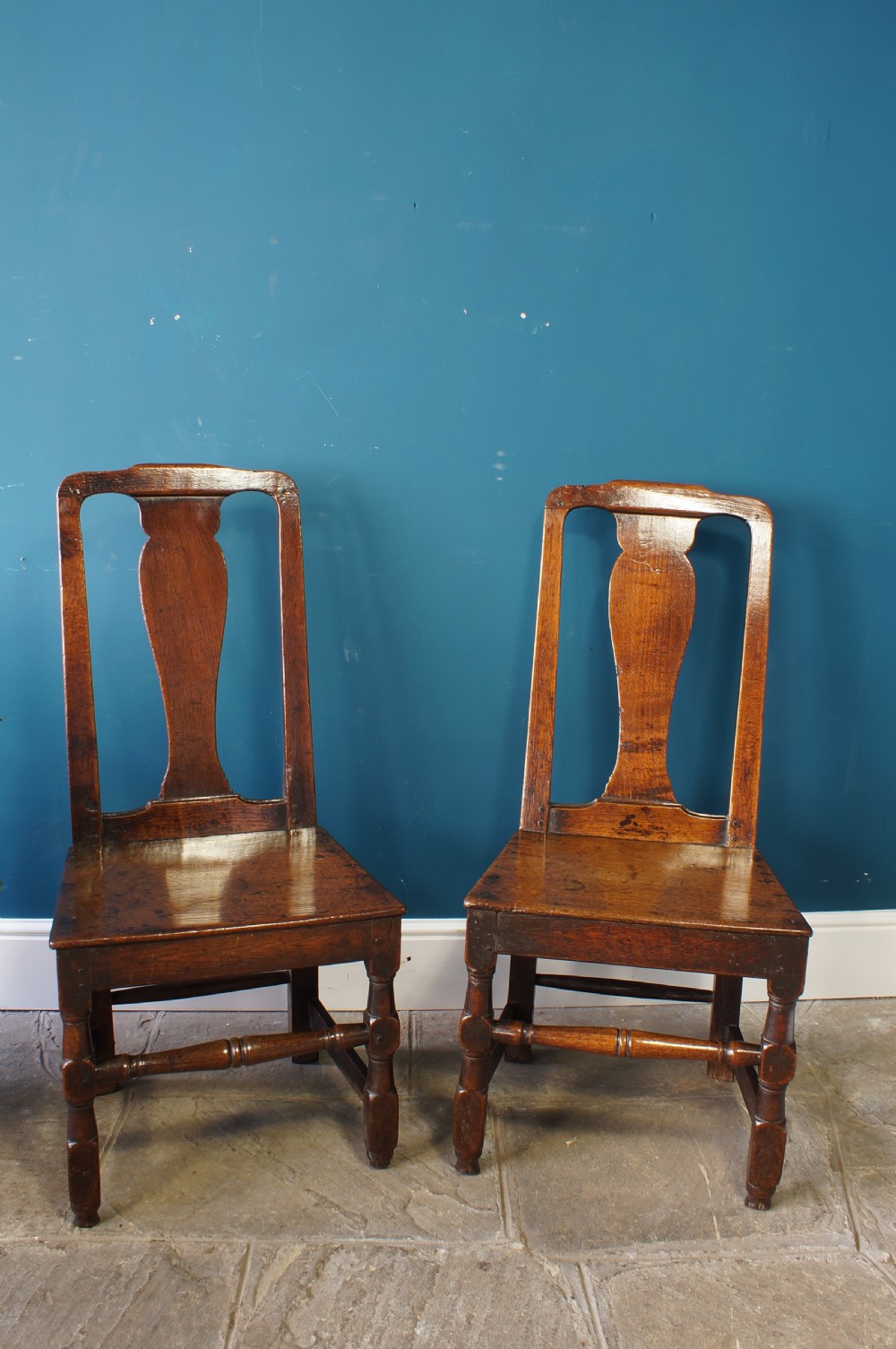 A pair of early 18th-century dark oak dining chairs with vase-shaped back splats, solid wooden seats, and turned front legs. View II