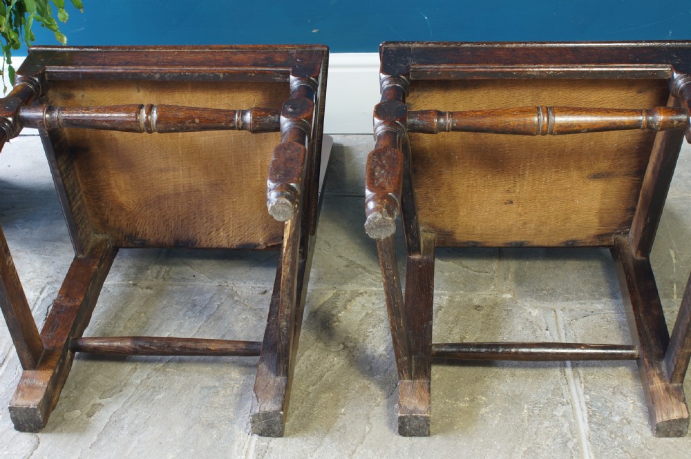 A pair of early 18th-century dark oak dining chairs with vase-shaped back splats, solid wooden seats, and turned front legs. View VIII