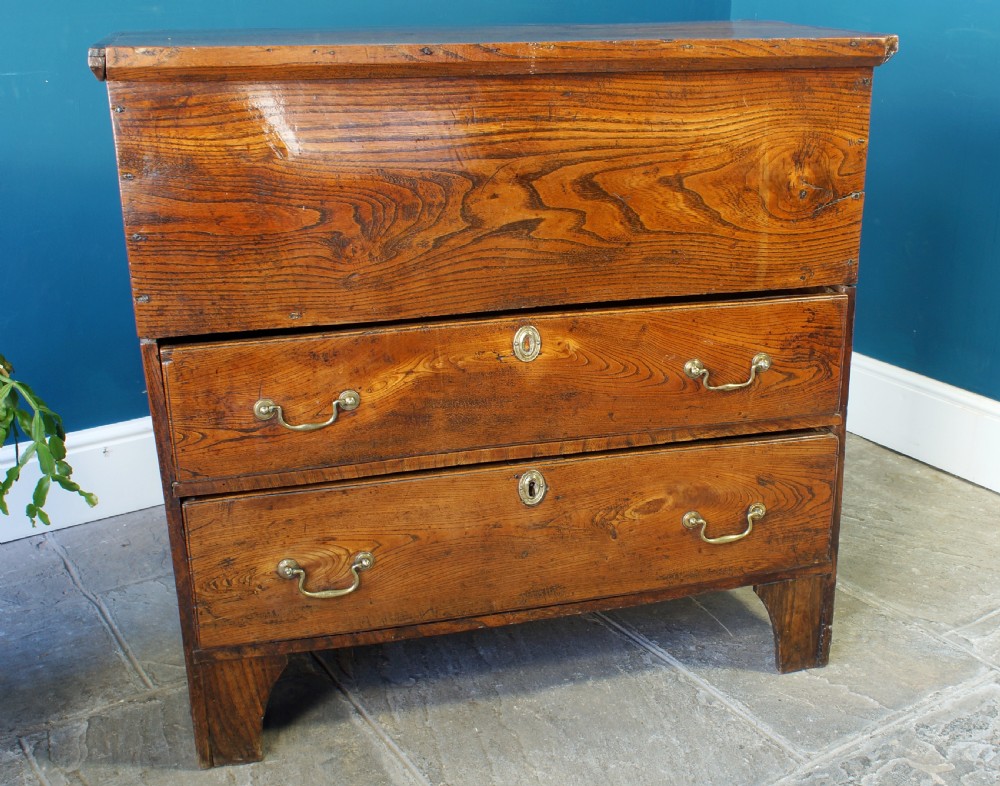 A Georgian elm mule chest featuring a hinged top lid over two wide drawers with brass swan-neck handles. View VI