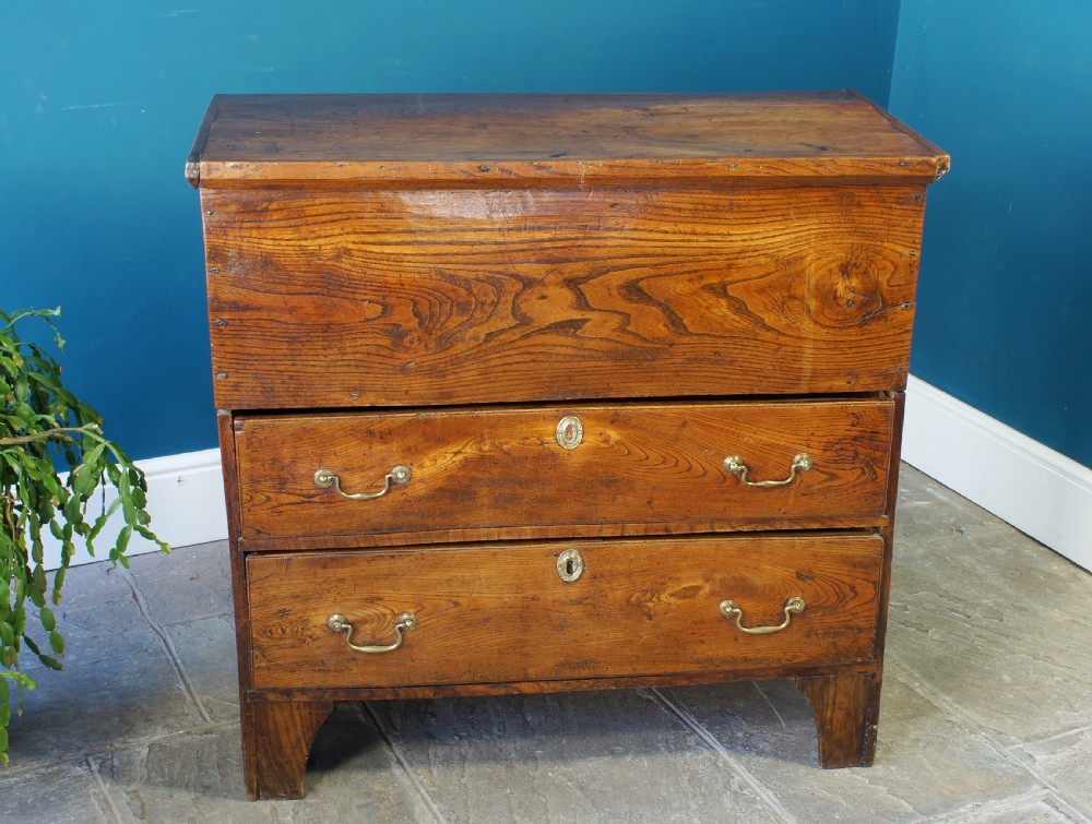 A Georgian elm mule chest featuring a hinged top lid over two wide drawers with brass swan-neck handles. View II