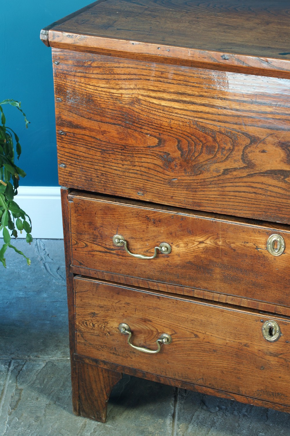 A Georgian elm mule chest featuring a hinged top lid over two wide drawers with brass swan-neck handles. View V