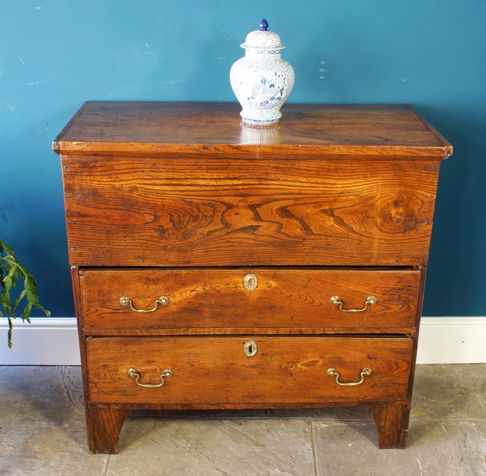 A Georgian elm mule chest featuring a hinged top lid over two wide drawers with brass swan-neck handles. View VII