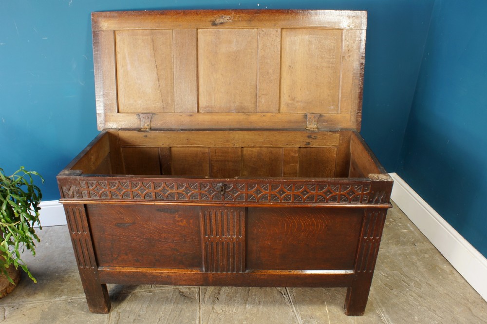 A 17th-century dark oak coffer with a carved geometric frieze, panelled front, and three-panel top lid. View III