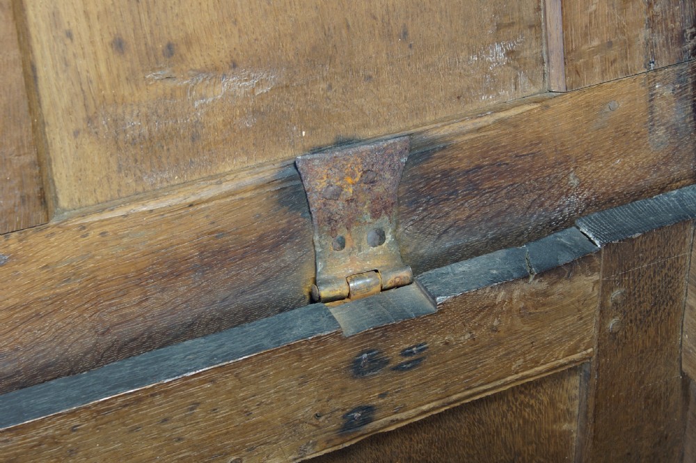 A 17th-century dark oak coffer with a carved geometric frieze, panelled front, and three-panel top lid. View VI