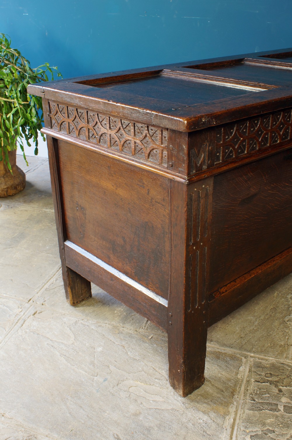 A 17th-century dark oak coffer with a carved geometric frieze, panelled front, and three-panel top lid. View XI