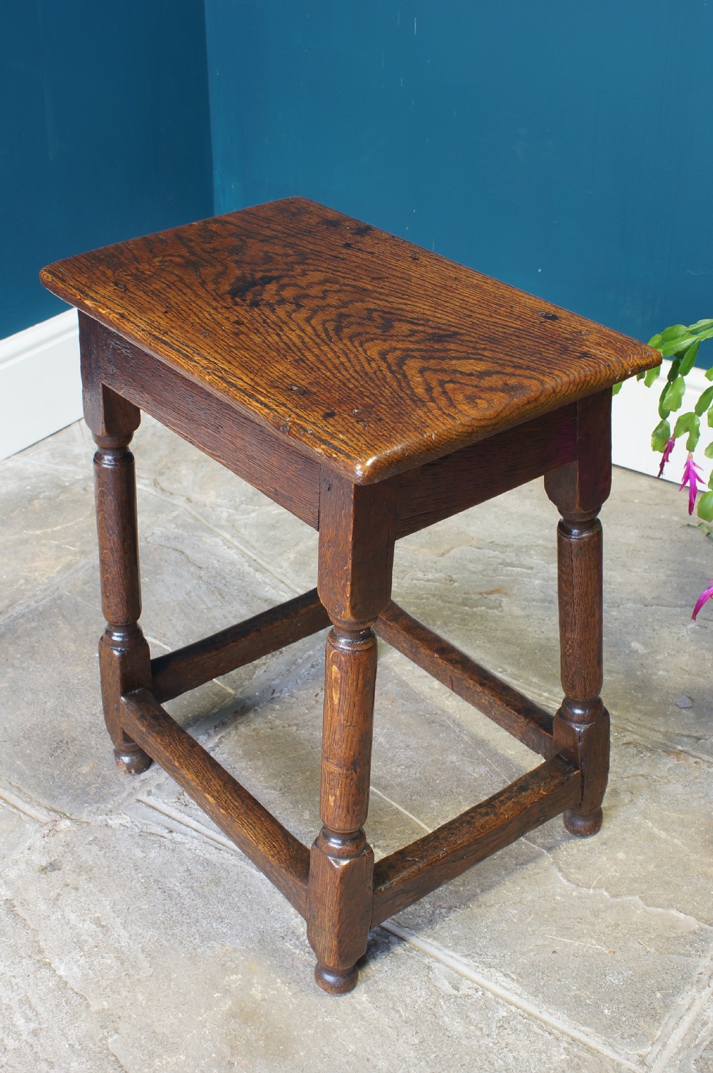 A dark oak rectangular joint stool featuring turned legs connected by rectangular stretchers and a moulded top.