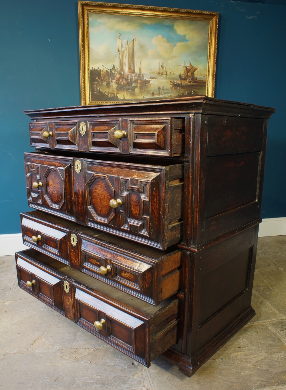 A dark oak 17th-century chest of drawers featuring geometric moulded drawer fronts and brass keyhole escutcheons. View IV