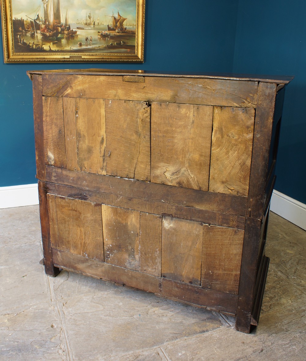 A dark oak 17th-century chest of drawers featuring geometric moulded drawer fronts and brass keyhole escutcheons. View V