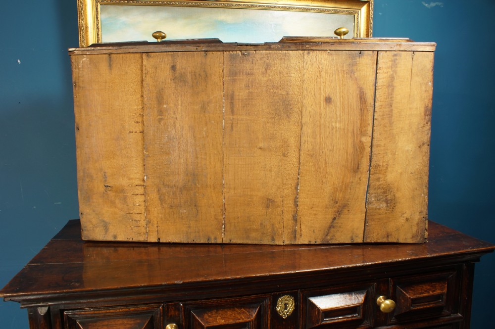 A dark oak 17th-century chest of drawers featuring geometric moulded drawer fronts and brass keyhole escutcheons. View VII