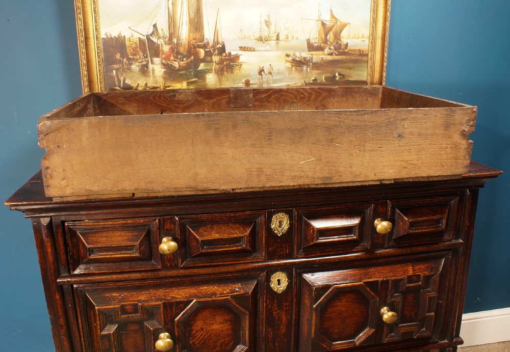 A dark oak 17th-century chest of drawers featuring geometric moulded drawer fronts and brass keyhole escutcheons. View VIII